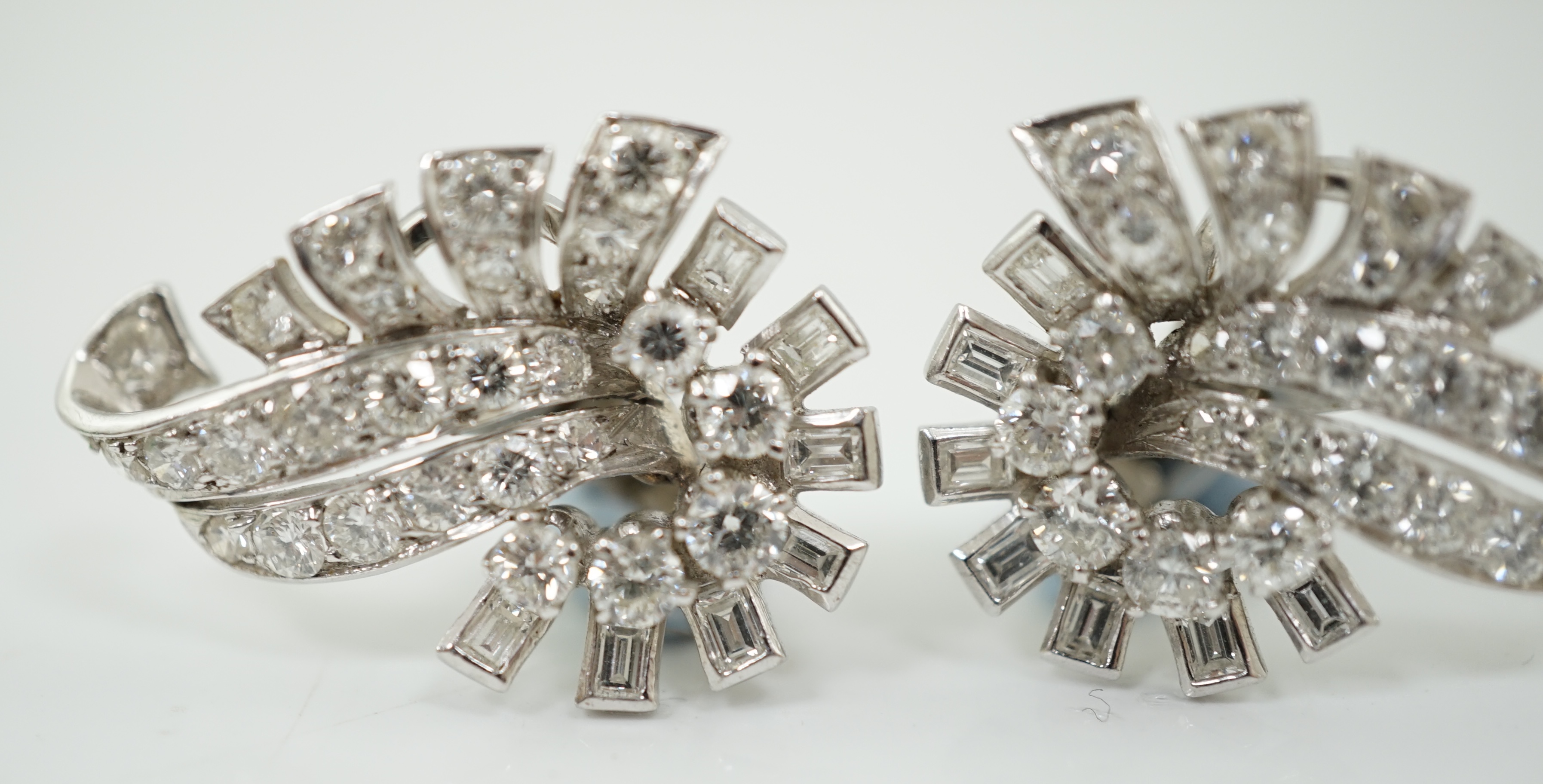 A pair of platinum and diamond cluster scroll ear clips